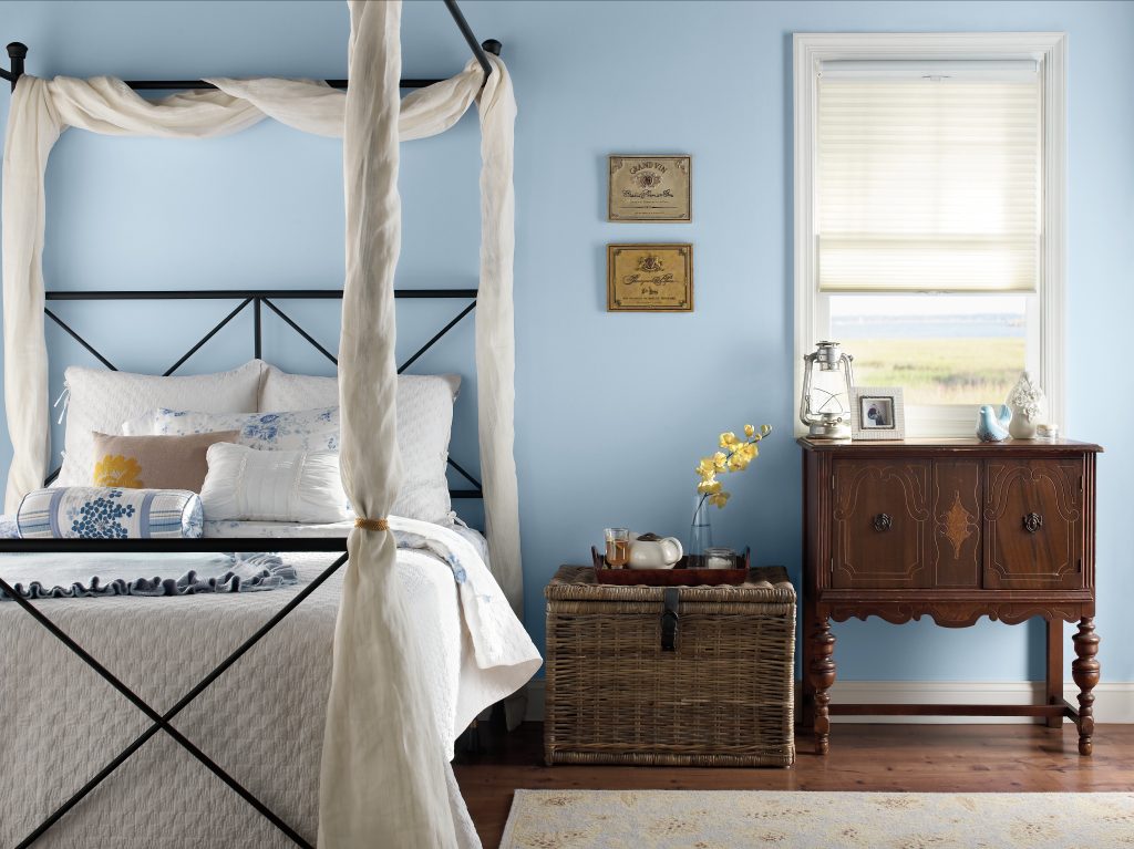 Serene bedroom with pastel blue Celestial Light MQ3-24 walls, soft white bedding and warm natural accents.