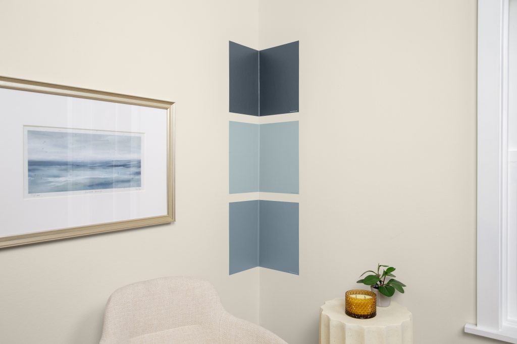 Three peel-and-stick paint samples in blue tones are displayed on a corner wall to show how each color responds to natural light.