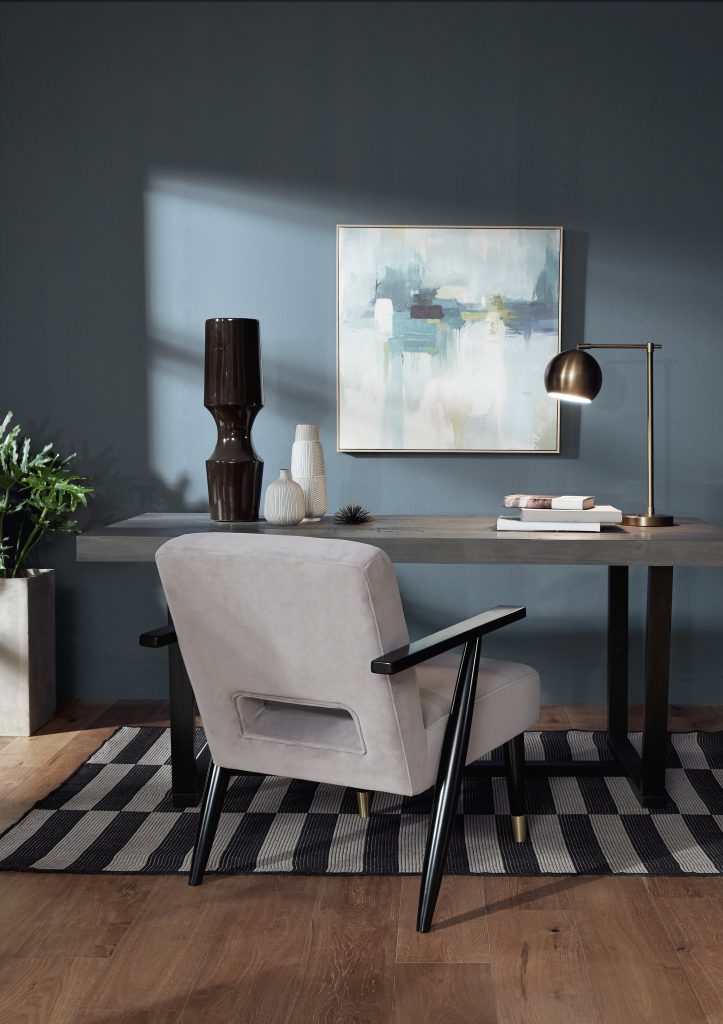 Cozy office space with muted blue walls painted in Adirondack Blue, wood desk, and upholstered chair.