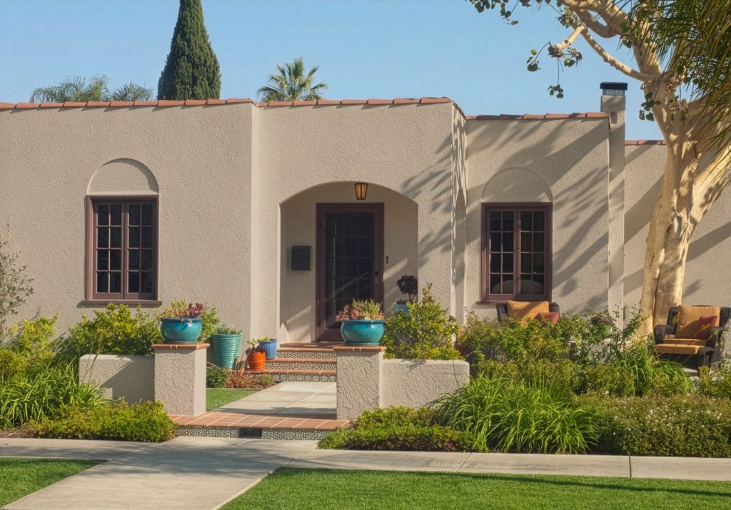 A Spanish-style stucco home featuring the BEHR Wheat Bread paint color with dark brown terracotta accents in Moroccan Henna, creating a warm, earthy BEHR Wheat Bread color palette.
