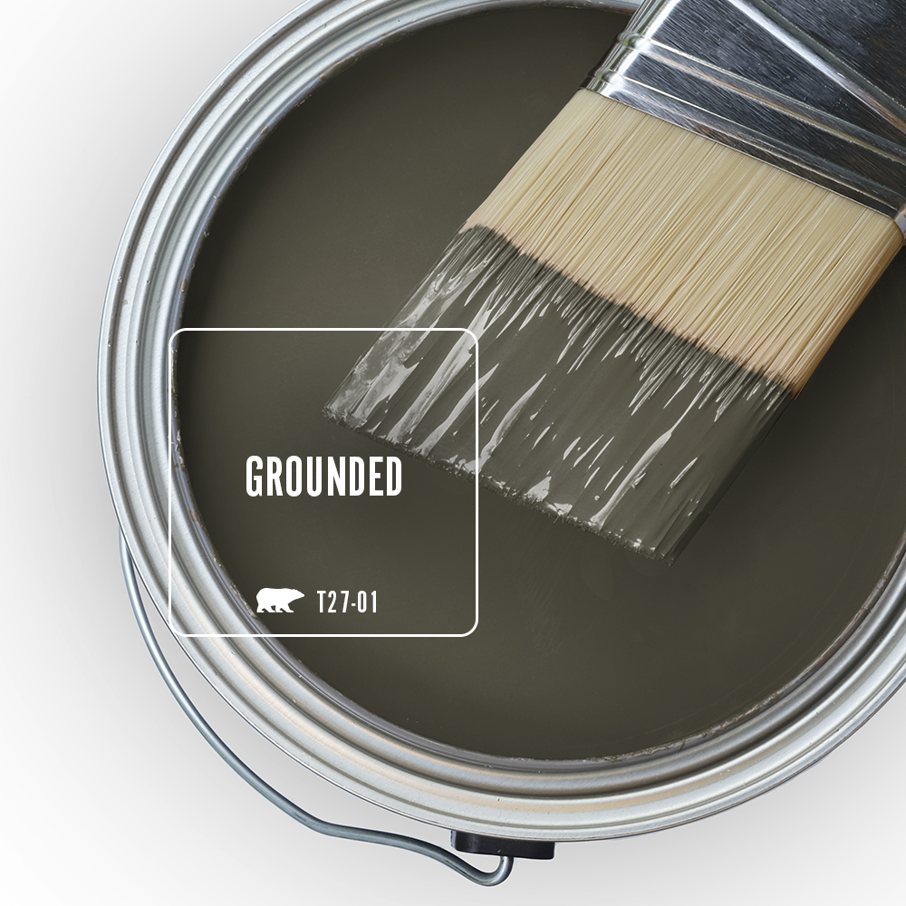 An open paint can filled with BEHR Grounded T27-01, with a paintbrush resting across the rim.
