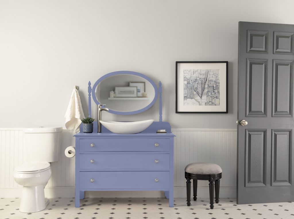 Bathroom with Cameo White soft neutral walls, white wainscoting, Vintage Ribbon blue painted vanity, gray door, patterned floor tile, and vintage-inspired accents for a romantic bathroom paint color idea.
