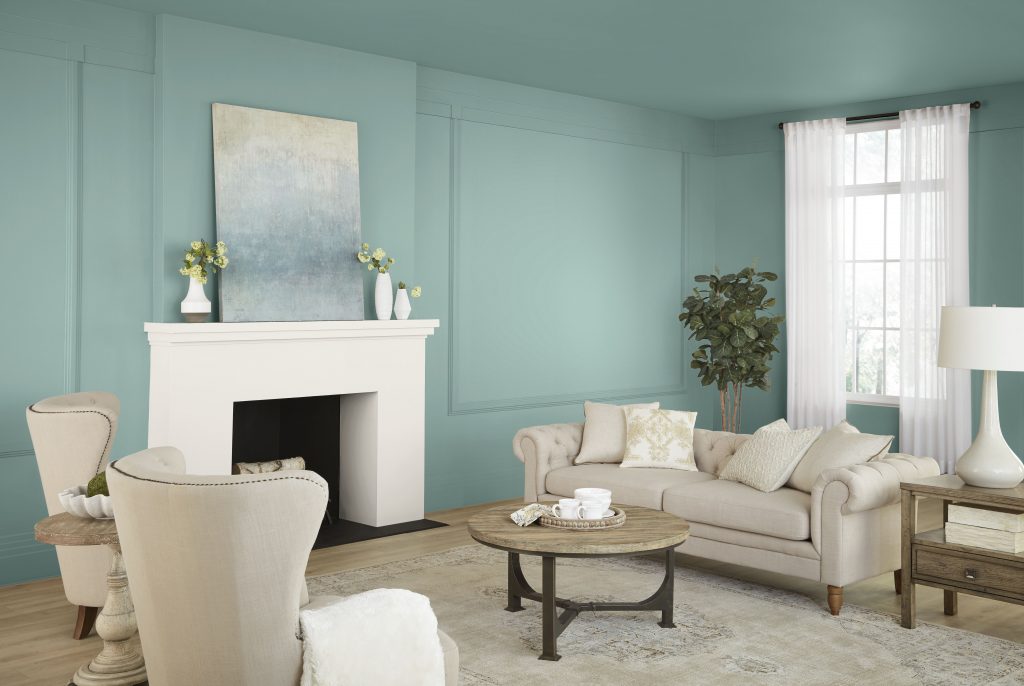 Living room with Opal Silk blue-green wall paint, white fireplace, neutral seating, natural textures, and warm wood accents for a soft romantic interior color palette.