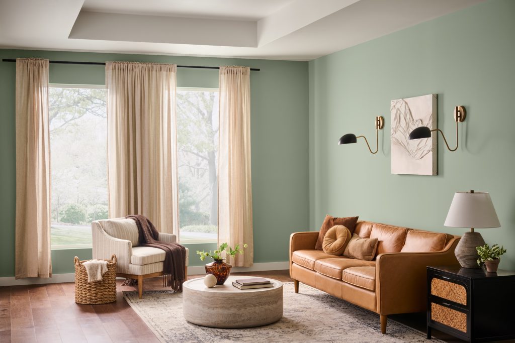 Living room with walls painted Jojoba N390-3, paired with warm leather seating, natural wood accents, creamy textiles, and soft natural light.