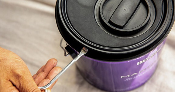 Person removing the simple pour lid with a paint key