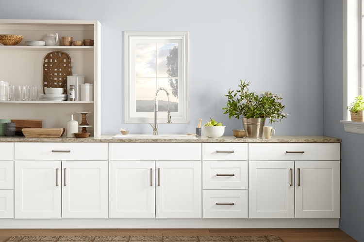 White kitchen cabinets with soft blue-gray walls, open shelving, and natural wood accents