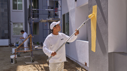 Pro painting an exterior wall of a commercial jobsite