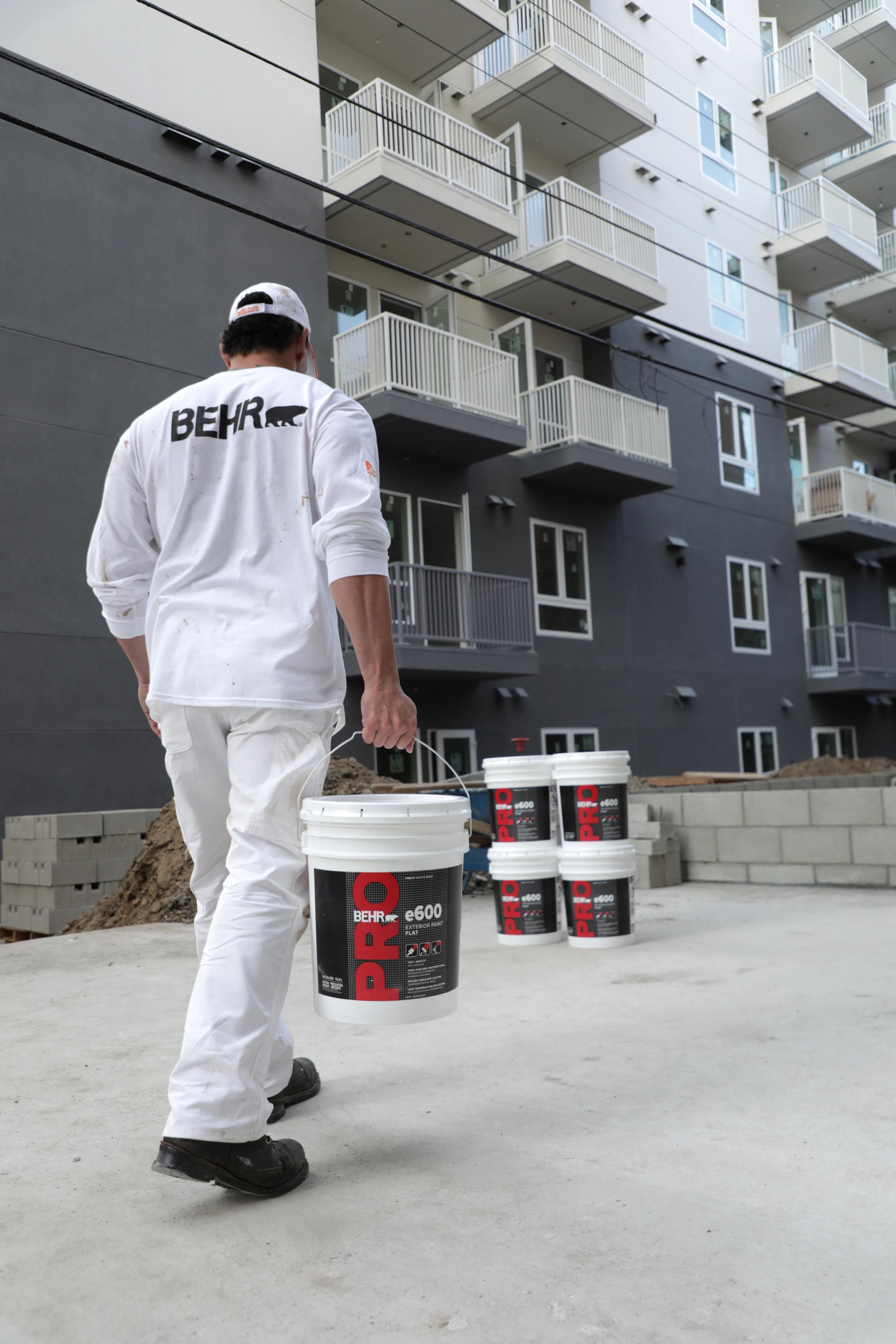 Pro Painter Carrying BEHR PRO e600 Exterior Paint to a Jobsite