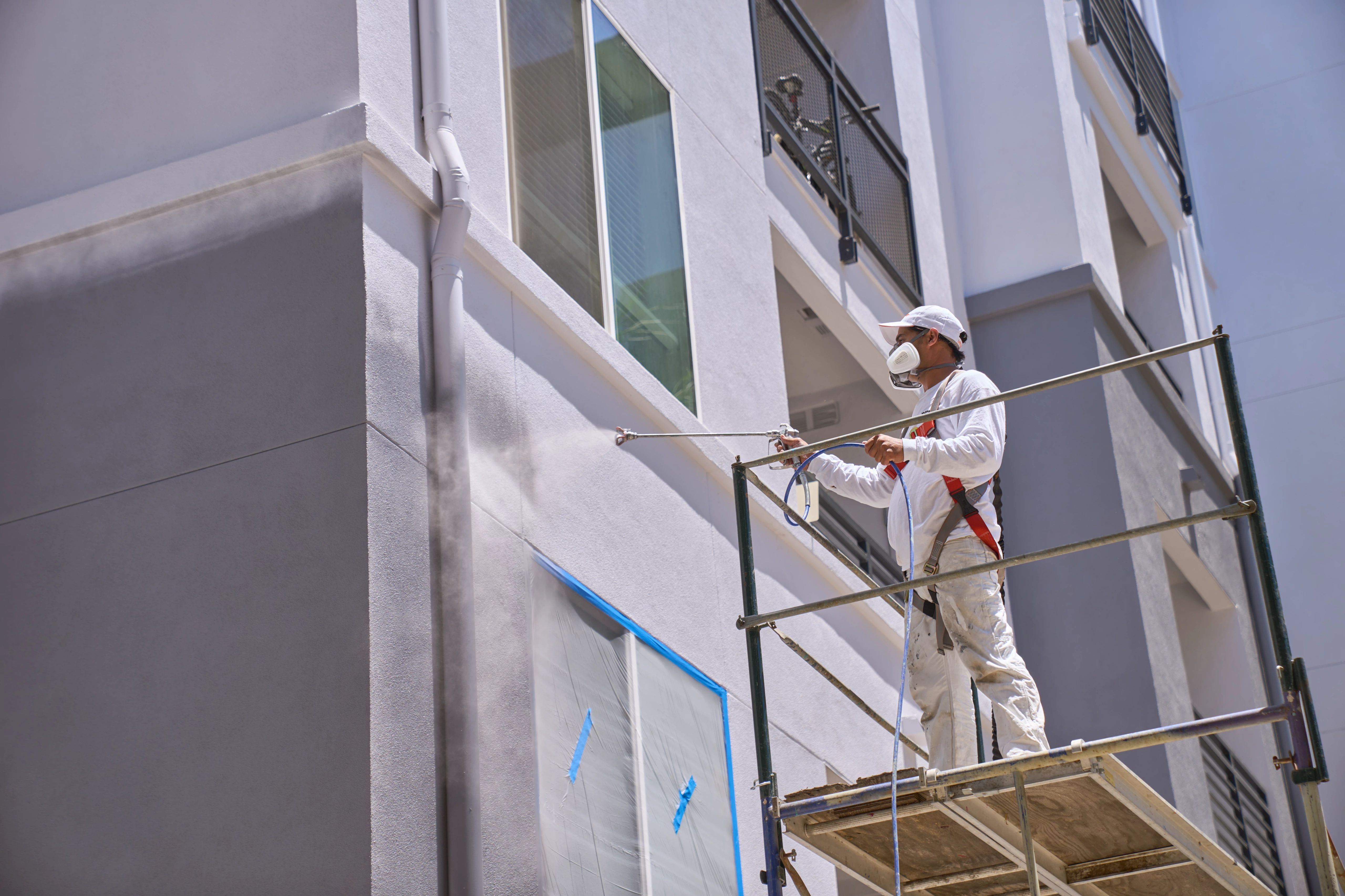 Professional Painter Spraying a Commercial Building